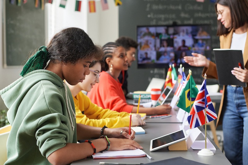 Open day advertising, students in class with various countries' table flags.