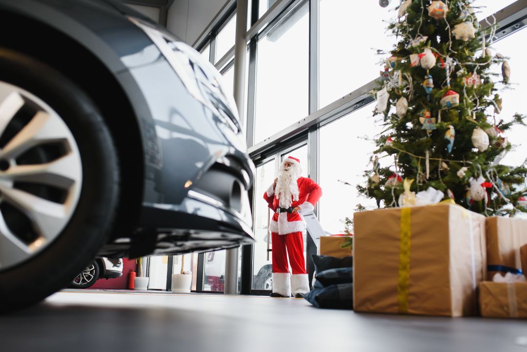 car sales banners, a person dressed up as Santa Claus in a dealership with Christmas decor