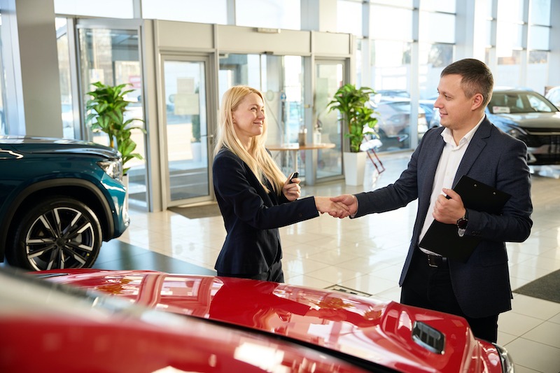 Car Dealership Branding, car salesman and customer shaking hands.