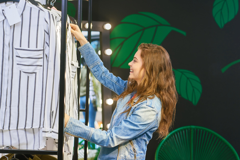 Earth Day Awareness, woman shopping near wall with green plant designs.