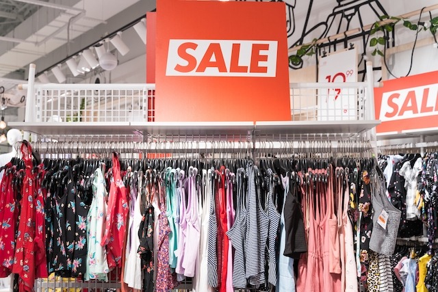 In-Store Promotions, rack of clothes with a sale sign.