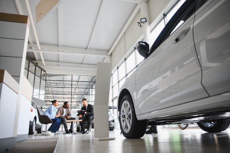 Car Dealership Branding, car salesman helping a couple pick a car.