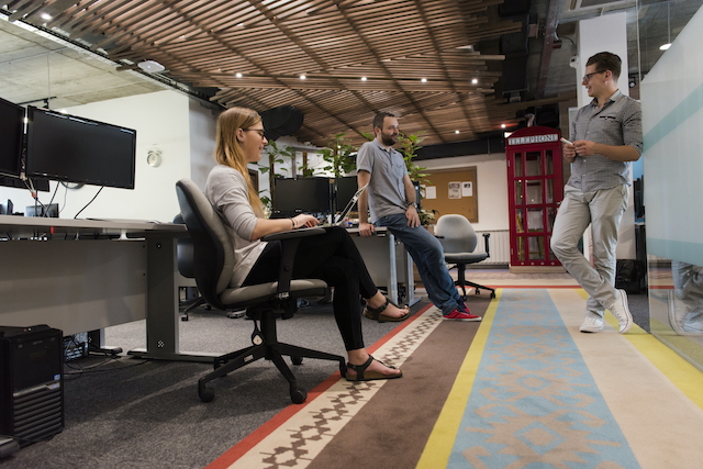 Renovate Office, three employees talking in office area with carpet floor designs.