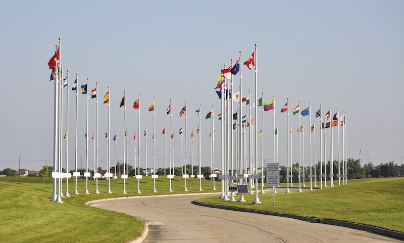 Flag pole bases explained, multiple national flags on flagpoles along the street.