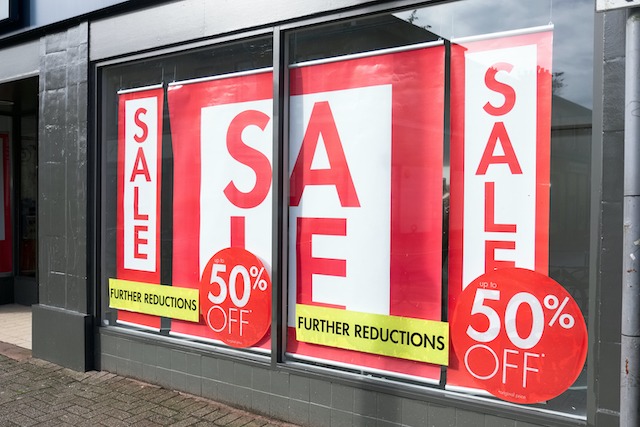 Digital vs physical marketing, large sale signs in a shop window.