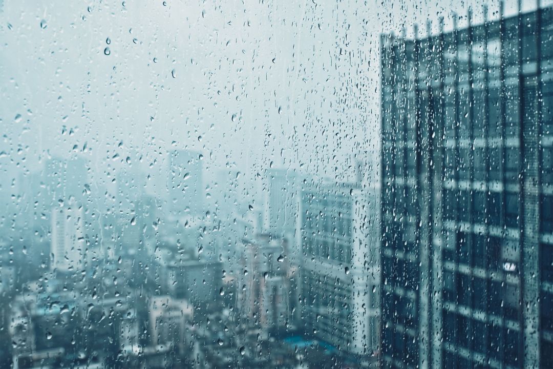 signs of a damaged flagpole, raindrops on the texture of a window glass with skyscrapers in the background