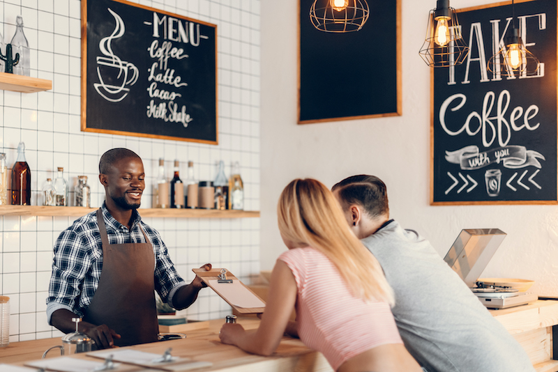Cafe Marketing Ideas, barista showing menu to customers.