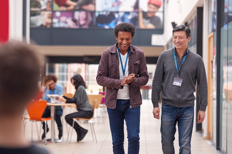 Open day advertising, students on campus with large digital signs on the wall.