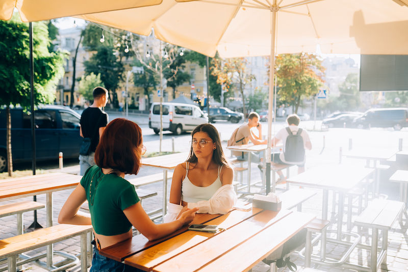 Cafe Marketing Ideas, people sitting under parasols outside cafe.