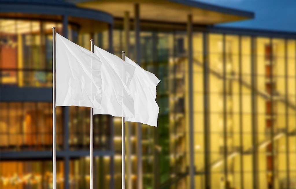What are high-quality flags made of, 3 white flags near buildings.