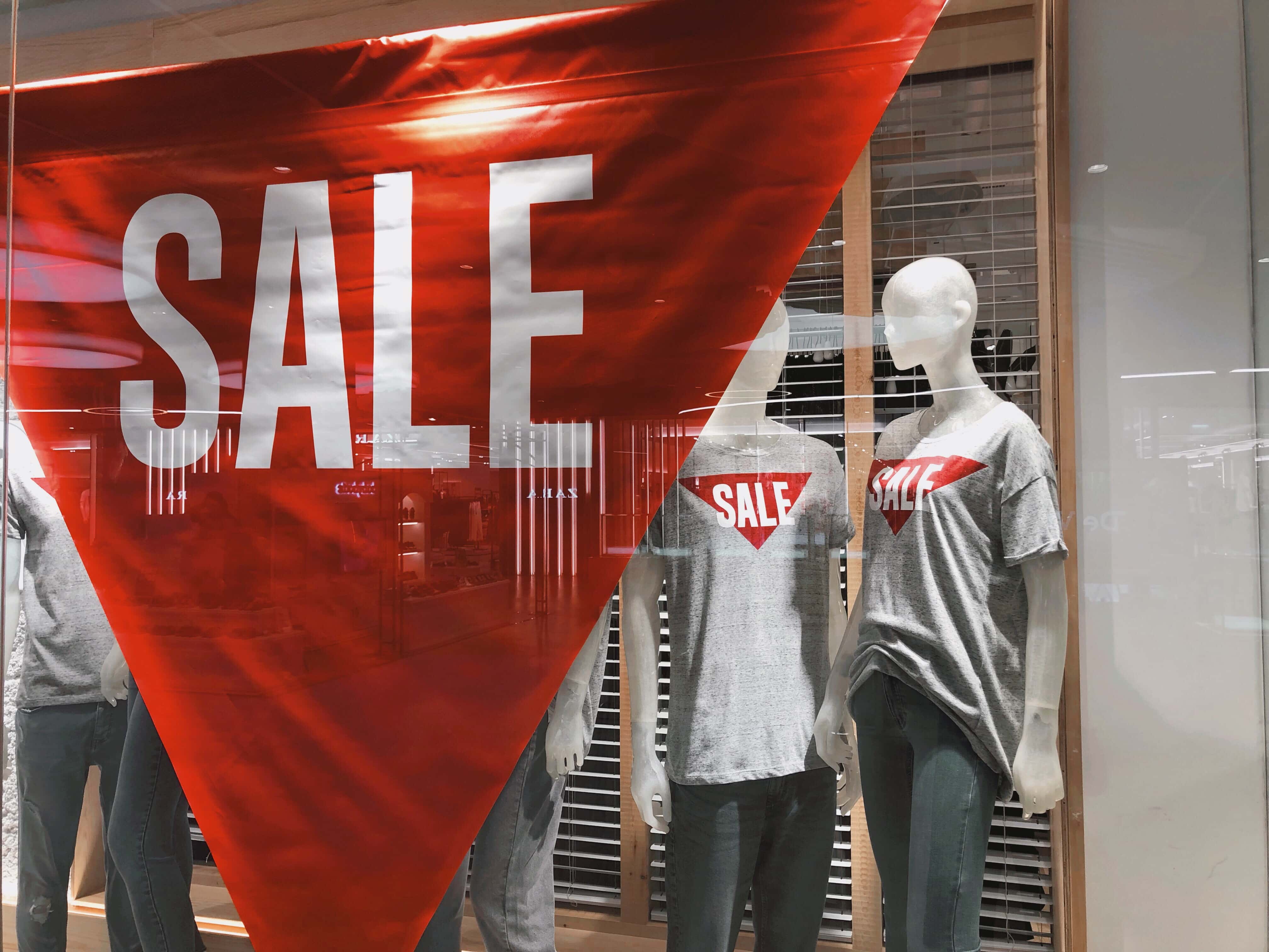 Boxing Day marketing tips, a large sale banner and mannequins wearing sale t-shirts in a window display.
