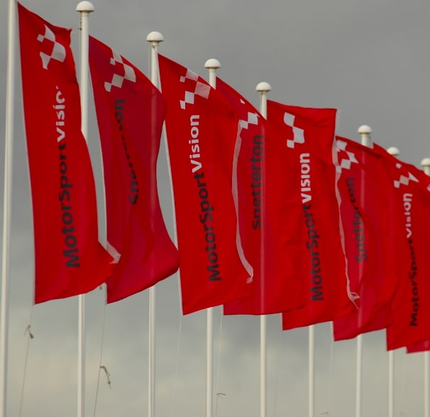 Advertising flags to promote business, multiple red branded flags in a row.