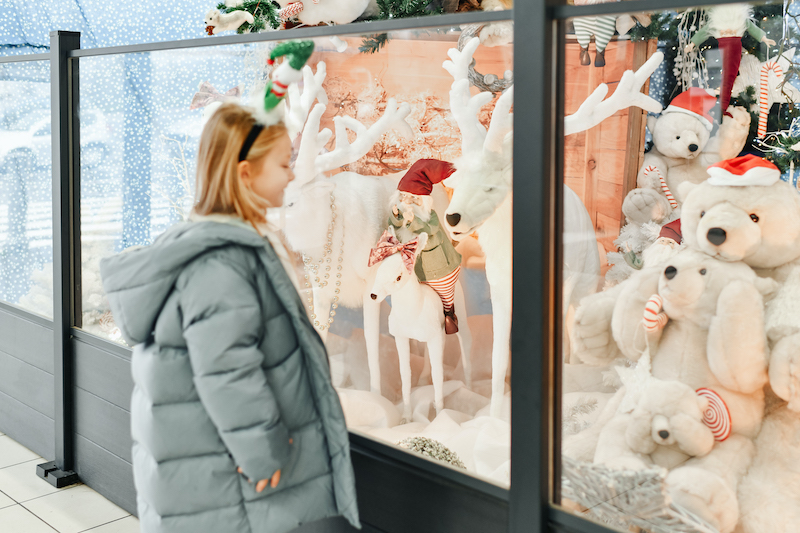 Create a Winter Wonderland, child looking into shop window with winter toys.