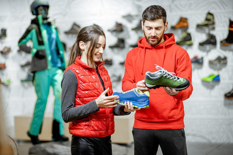 Sports apparel store, man and woman buying sports shoes in store