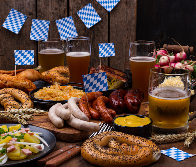 Oktoberfest advertising, various German dishes and beers with flags and bunting.