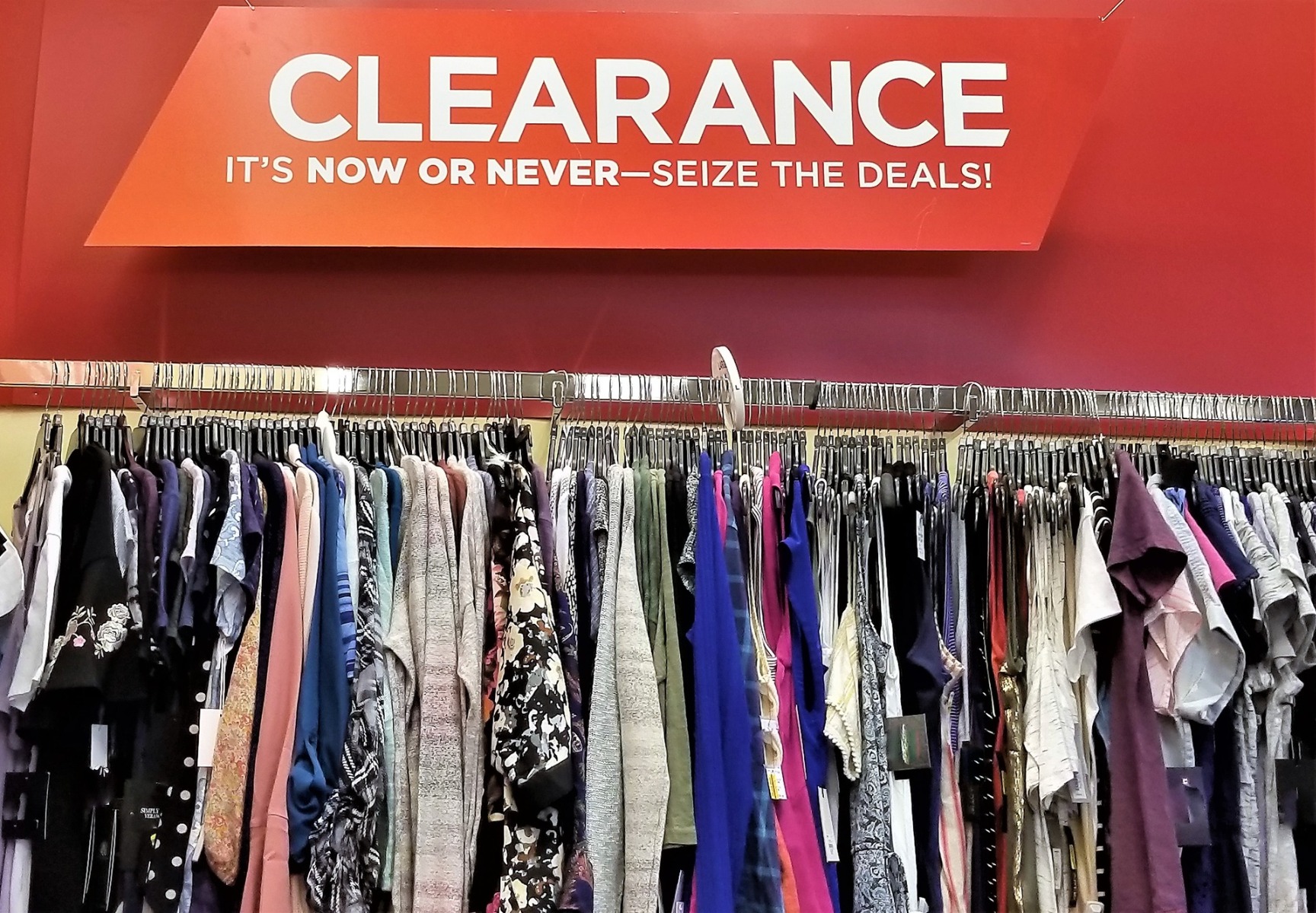 Two women posing with discount boards in front of a clearance sale